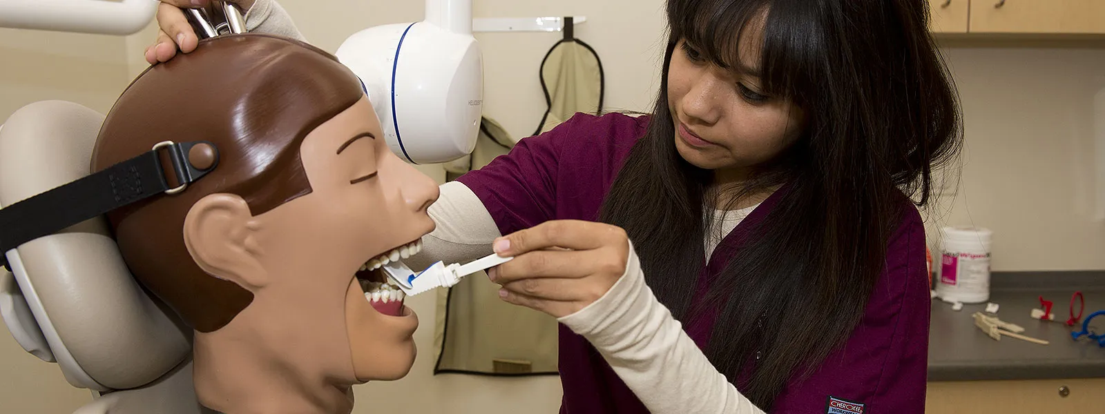 Female dental technician working with equipment on practice manikin.