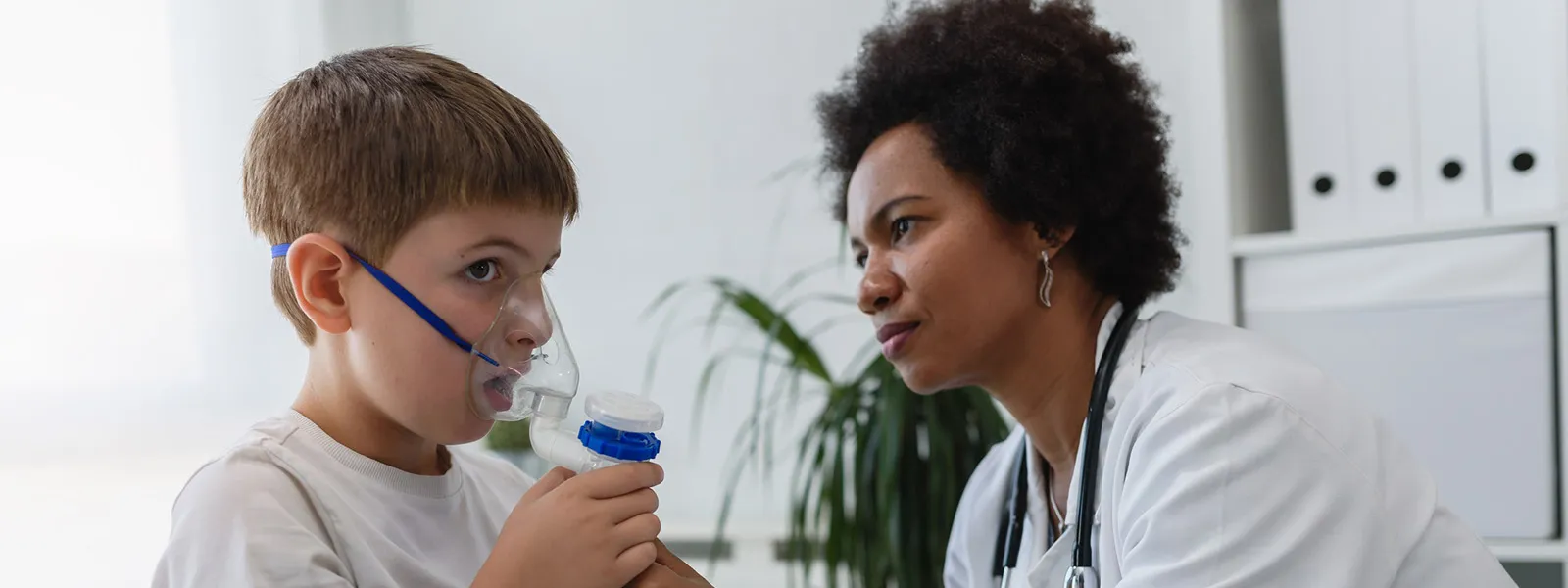 A nurse administering inhalation treatment to a young child.