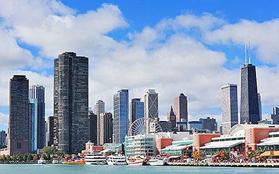 Chicago city downtown urban skyline with skyscrapers over Lake Michigan with cloudy blue sky.