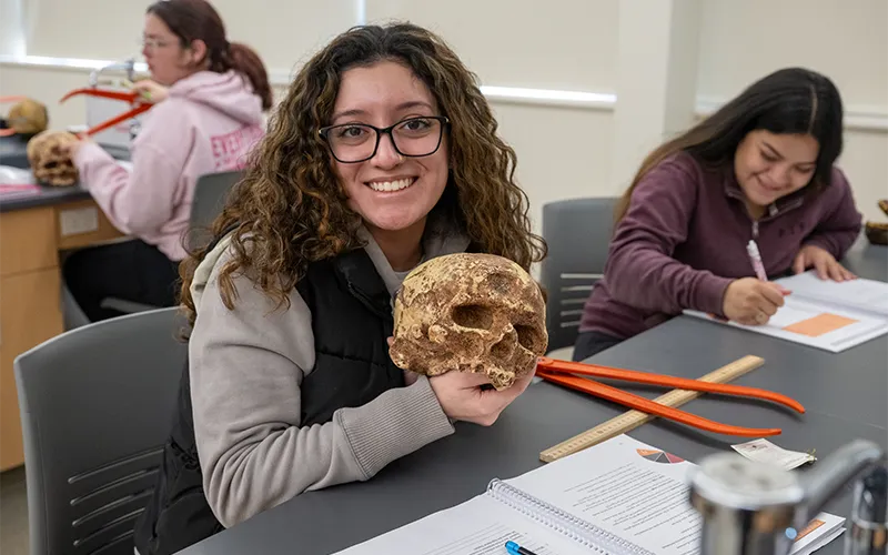 Estudiante en clase de ciencias sosteniendo una calavera
