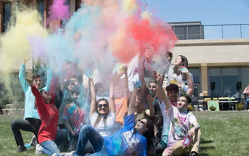 Group of students throwing colored chalk into the air.