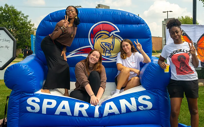 students outside in a giant chair smiling