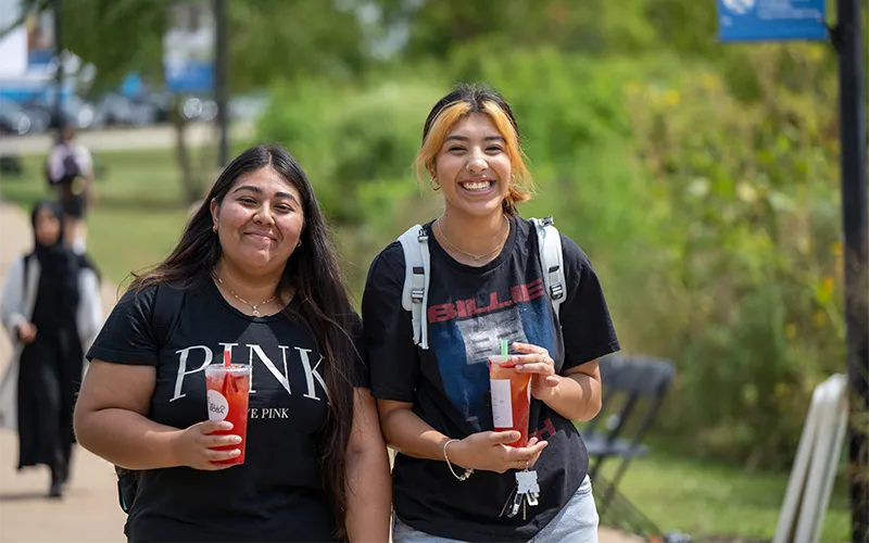 Estudiantes sonriendo mientras caminan juntos al aire libre.