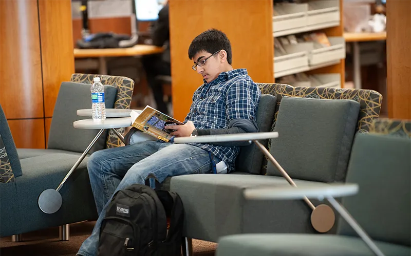 Un estudiante leyendo un libro en el vestíbulo.