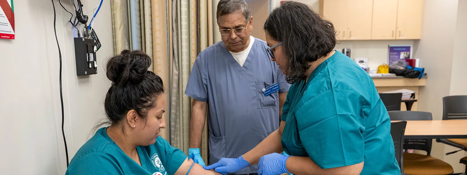 Instructor teaching a student to draw blood