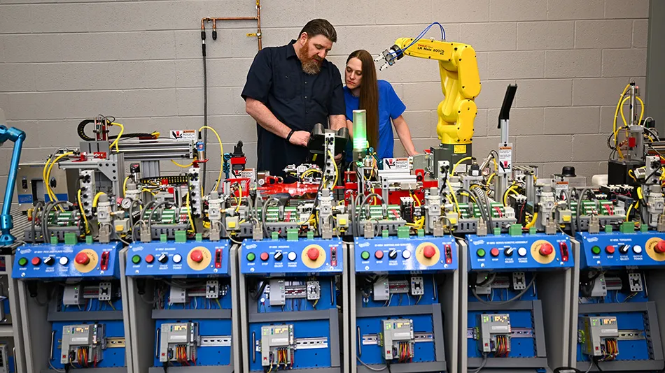 Instructor with student looking at a robotic manufacturing arm