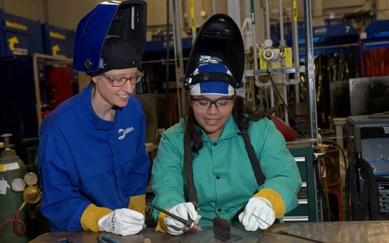 Two students work on a welding assignment