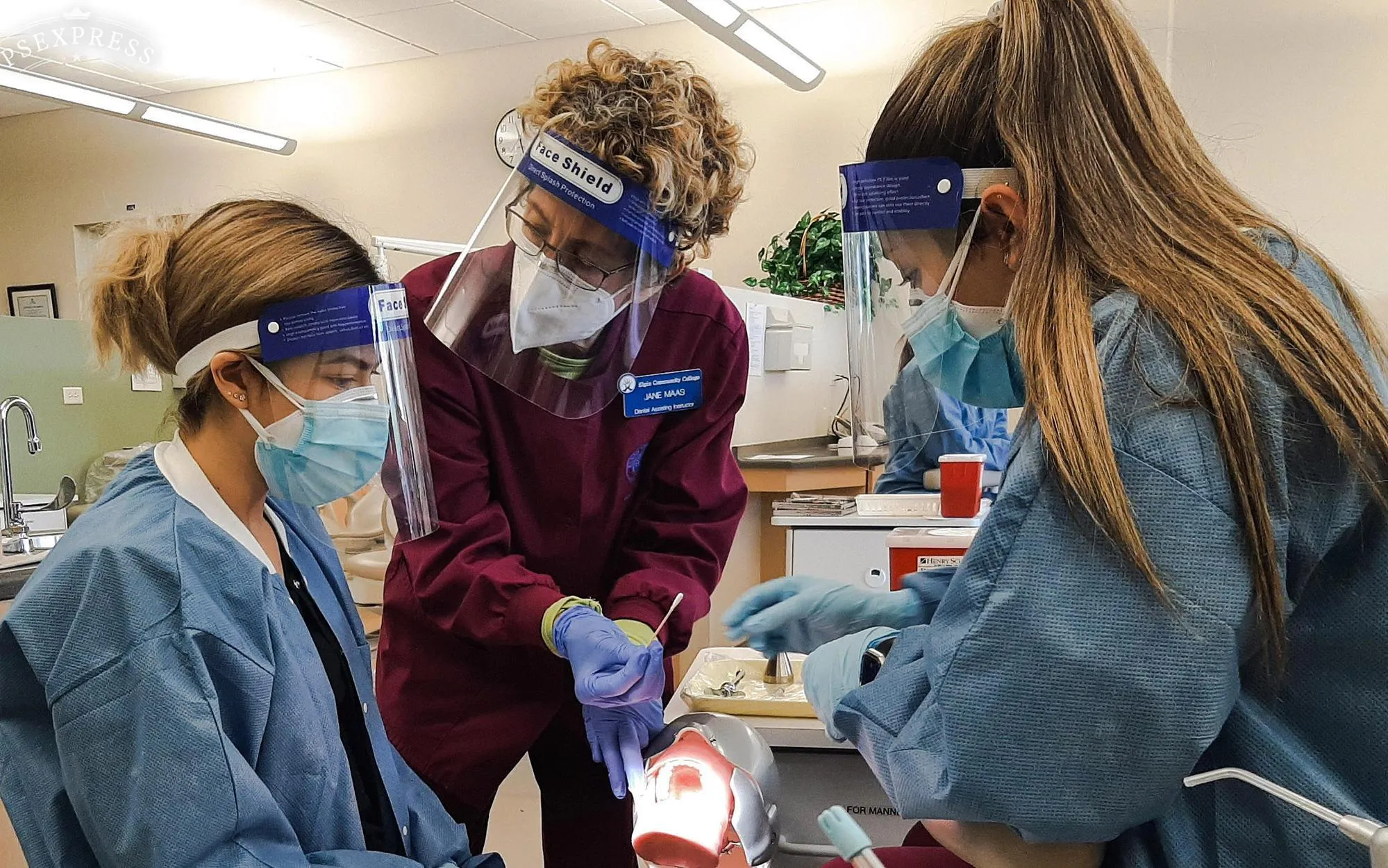 Jane Maas, dental assisting adjunct faculty, demonstrates anesthetic application for two students