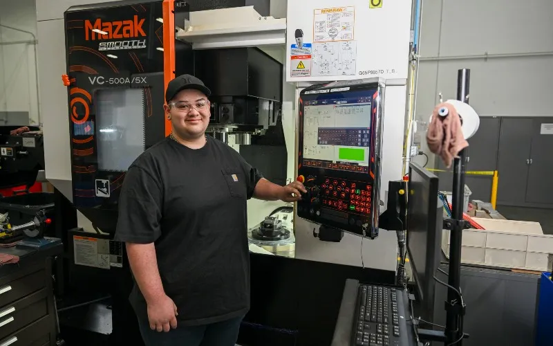 ECC student Soren Erickson poses next to equipment at his work, Haumiller.