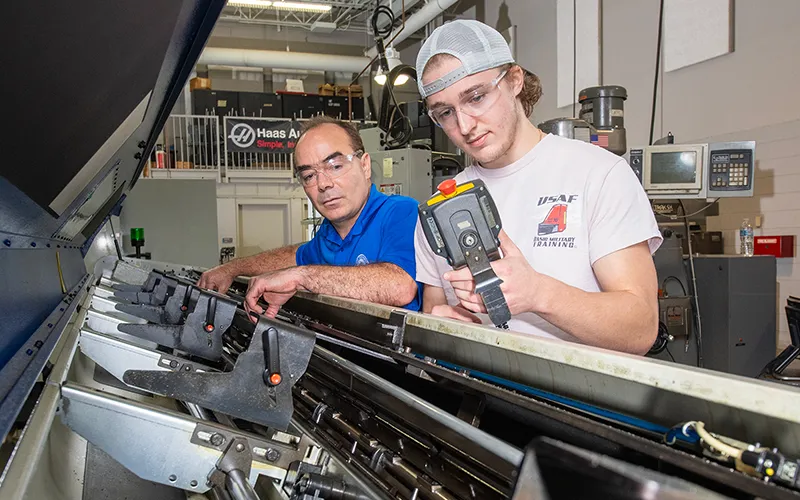 Umberto Tinajero, an instructor of Industrial Manufacturing Technology (IMT) and Computer Integrated Manufacturing (CIM) at Elgin Community College (ECC) assists a student