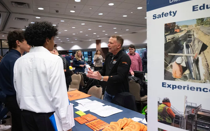 A vendor at the fall 2025 apprenticeship expo speaks to two individuals.