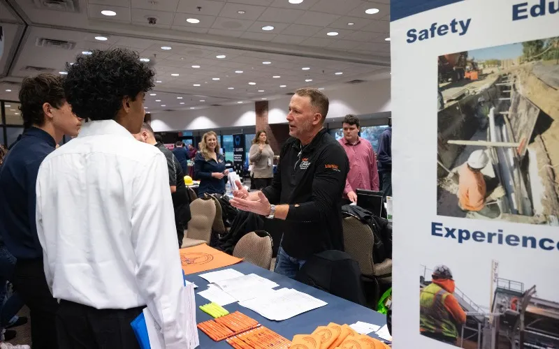 An employer at the 2025 Apprenticeship Expo at ECC chats with two individuals.