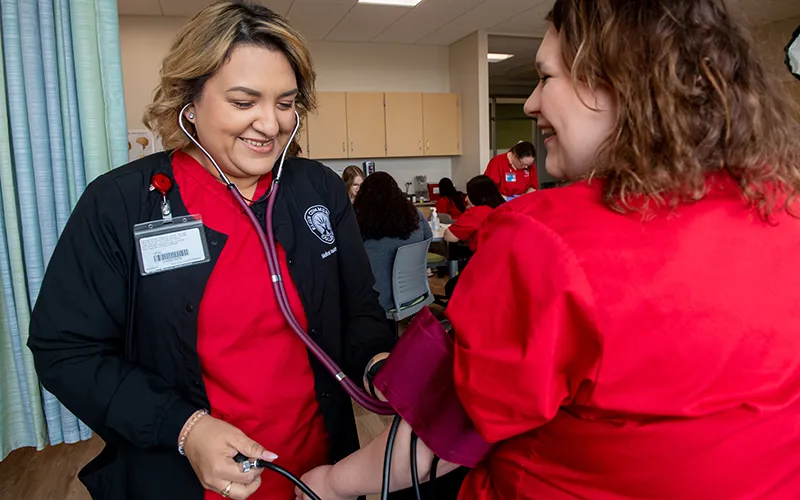 ECC medical assisting program graduate Nina Wadz practices on a classmate