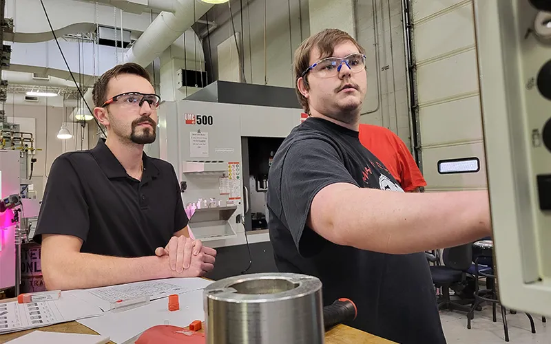 ECC Alum and Instructor Anthony Bellavia is seen working with student Henry Piehl in a manufacturing classroom.