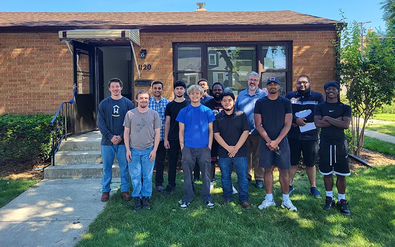 Los alumnos del programa de capacitación para recién llegados sobre eficiencia energética de ECC/ComEd posan juntos para una foto frente a una casa que visitaron como parte de la clase.