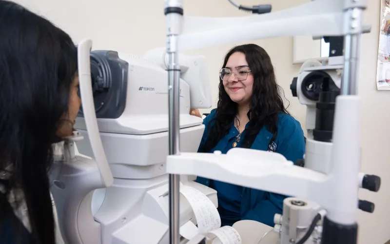 ECC Alum Daisy Solorzano works with ophthalmic equipment and a student in a Ophthalmic Technician classroom.