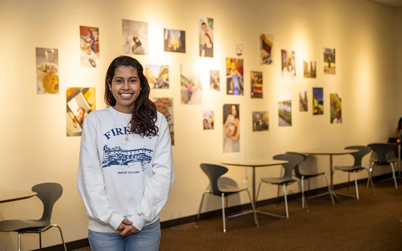 ECC student Esbeyda Garcia Diaz stands in front of the Venezuelan Art Exhibition, titled “Life, Liberty, and the Pursuit of Happiness