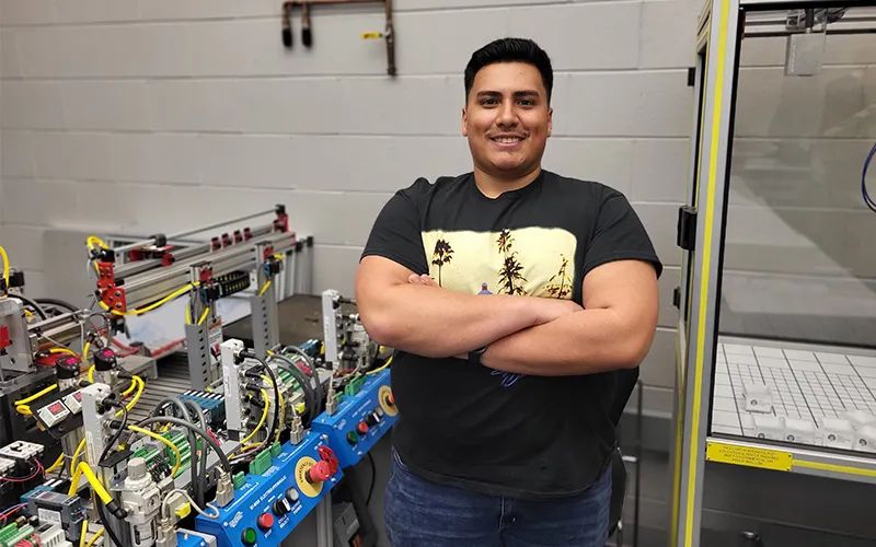 ECC student Geovany Medina poses in one of his classrooms next to equipment.