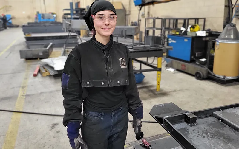 Jasmin De La Torre, ECC student and Advance Lifts employee, poses next to her work station.