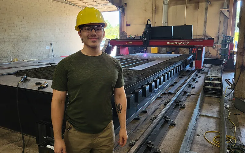 Joseph Lortie, ECC student and Advance Lifts employee, poses next to his work station.