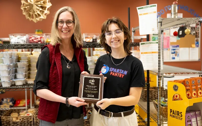 ECC President Peggy Heinrich and Alum/Former Spartan Pantry Officer Sid Perkins poses with the 2025 Feed the Need Campus Drive award.