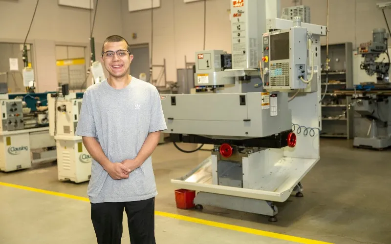 ECC student Ryan Reid poses in a manufacturing classroom.
