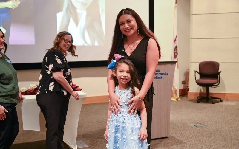Yeni Elizalde, graduada de ECC, posa con su hija en la ceremonia de entrega de insignias de enfermería de la primavera de 2026.