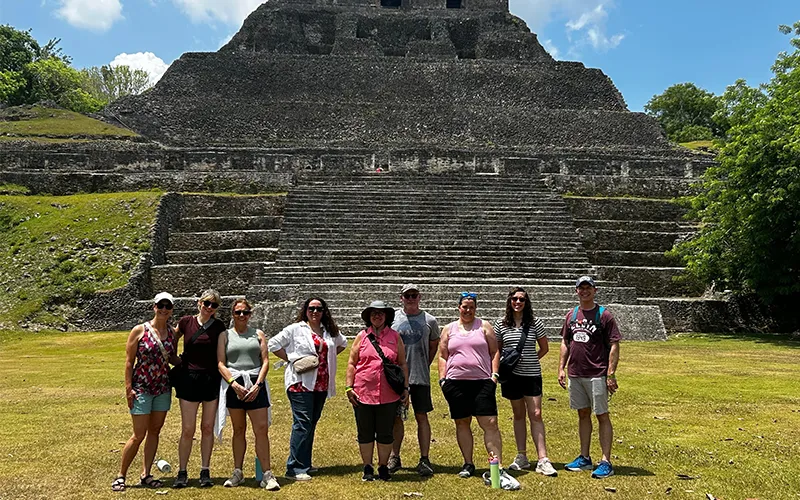 ECC employees pose in front of large ancient Maya archaeological site Caracol during their Belize trip.