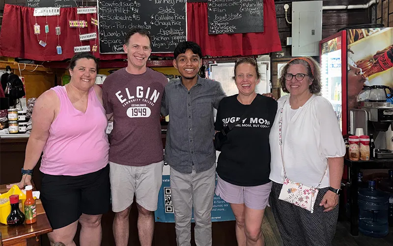 ECC employees pose with a local student in Belize who served them dinner at a local restaurant.