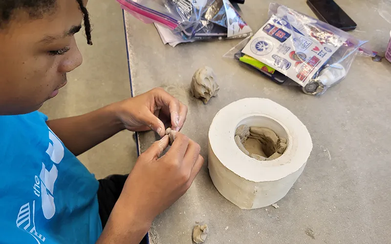 A member from the Boys & Girls Club of North Central Illinois in Elgin works on pottery in an ECC classroom during a visit.