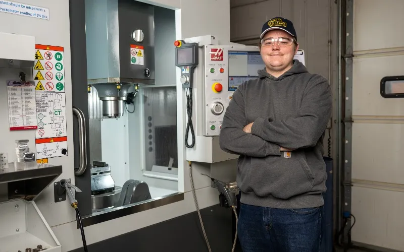 ECC student and apprentice Henry Piehl poses next to equipment at his job at Haumiller Engineering in South Elgin.