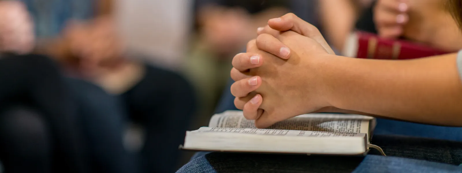 Manos rezando encima de la biblia