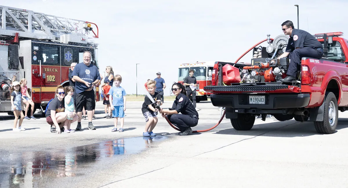 Fire personal demonstrating how to work a fire hose at a touch a truck event.