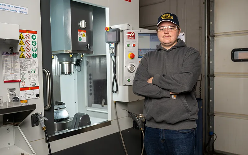 Advanced manufacturing student smiling and standing with his arms crossed
