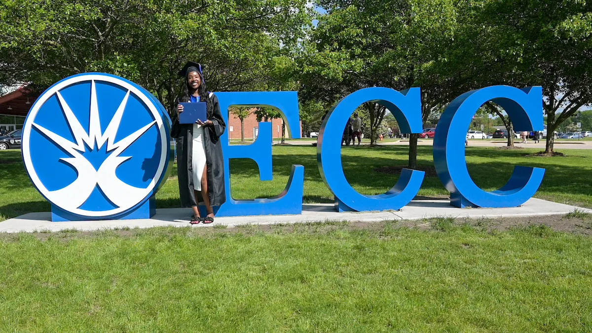 ECC Graduate Stands by ECC Sign