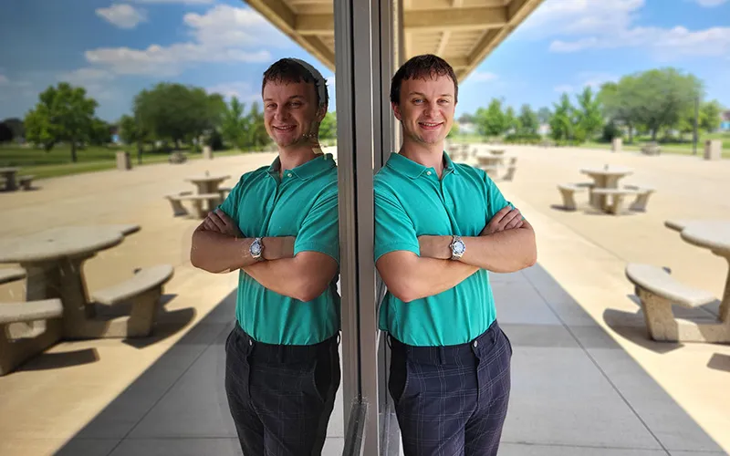 A student stands next to a window