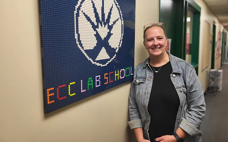 Kristina Brown stands near a LEGO art piece in the childcare center