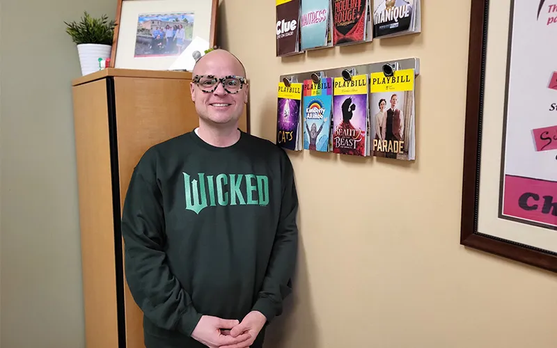 Tracy Vittone stands in his office with his display of playbills