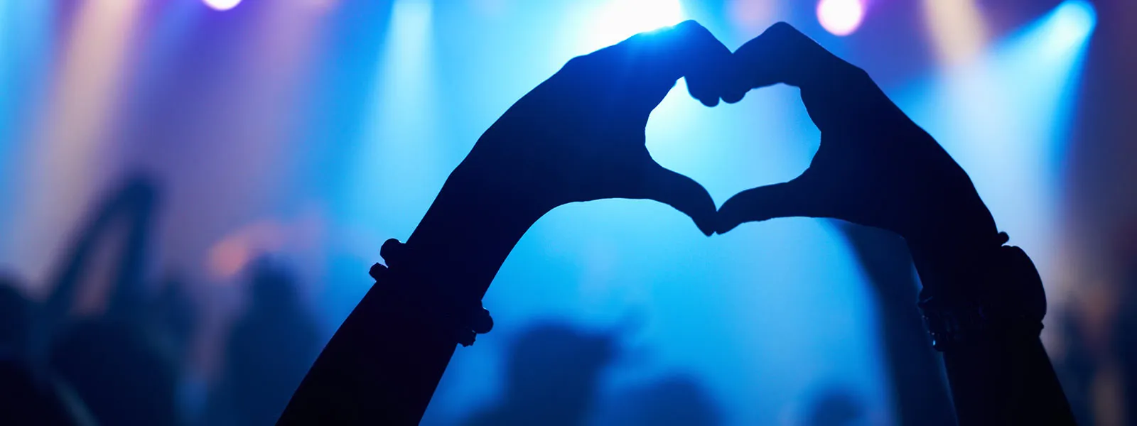 A young person gesturing towards the stage while enjoying a band perform.