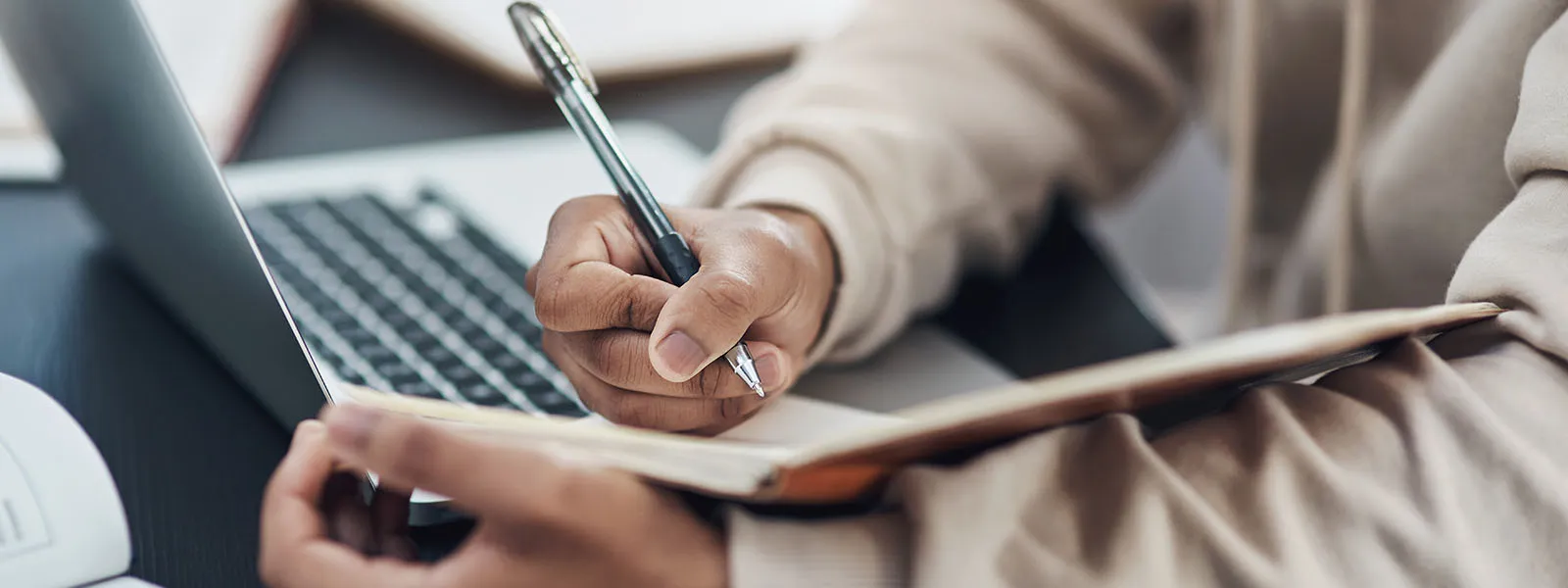 Foto de un hombre irreconocible escribiendo en un cuaderno mientras trabaja desde casa - foto de archivo