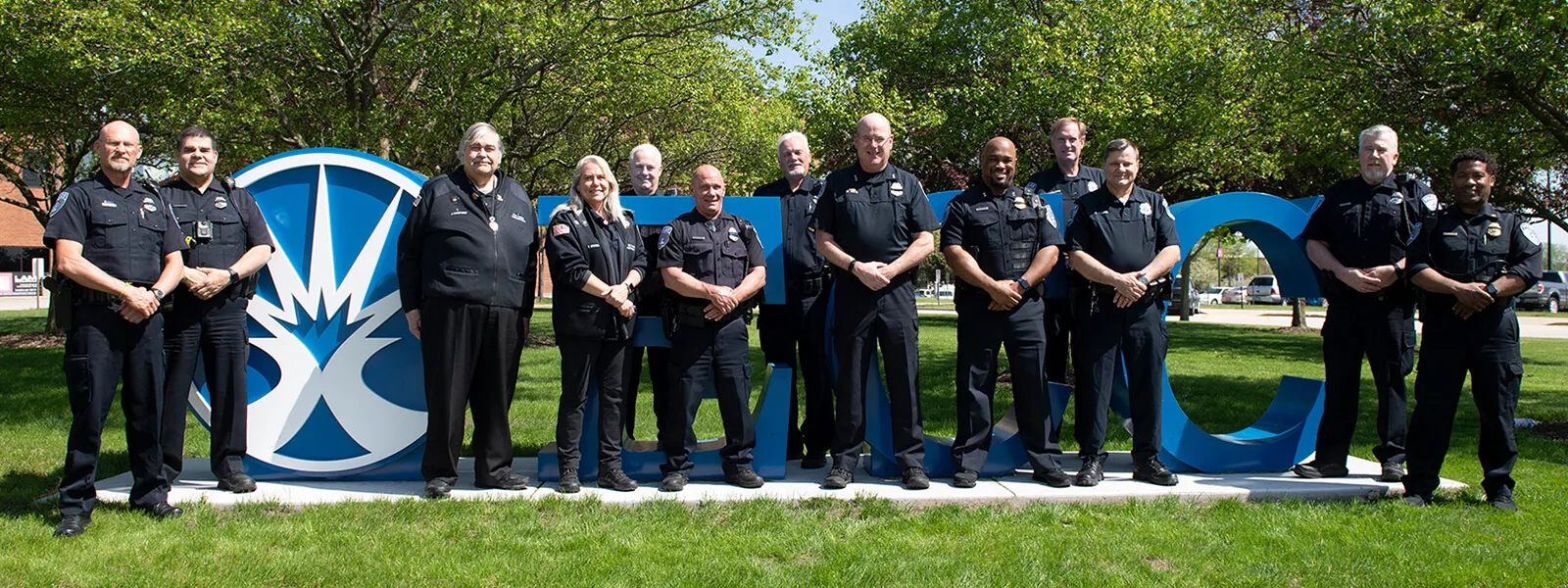 The ECC PD standing outside in front of the 3D ECC signage on campus