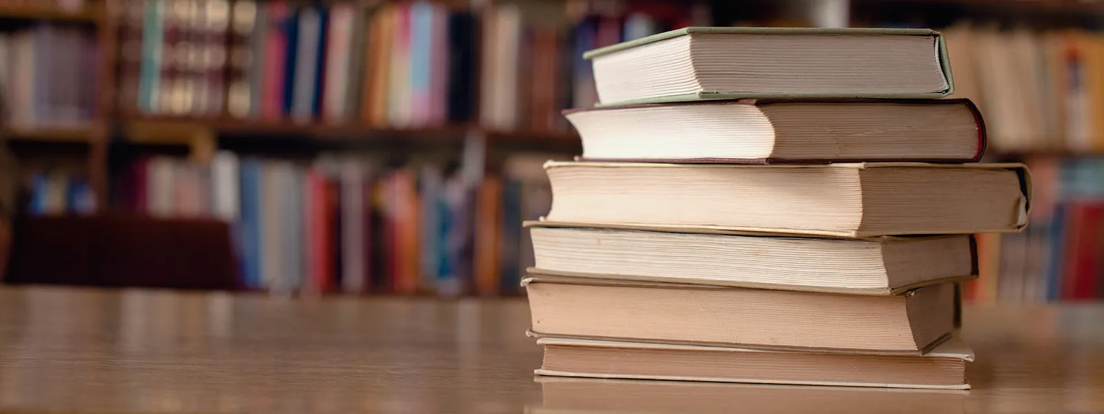 pile of books on a desk.