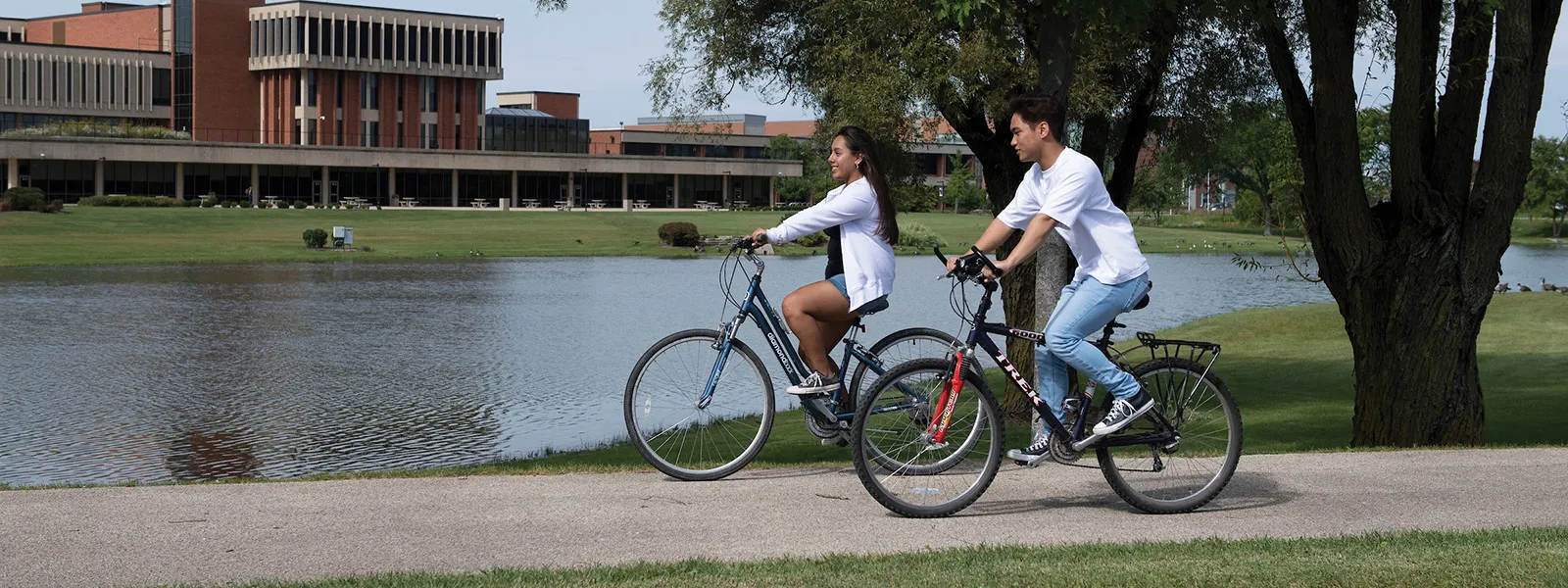 dos personas en bicicleta en el campus comunitario de Elgin