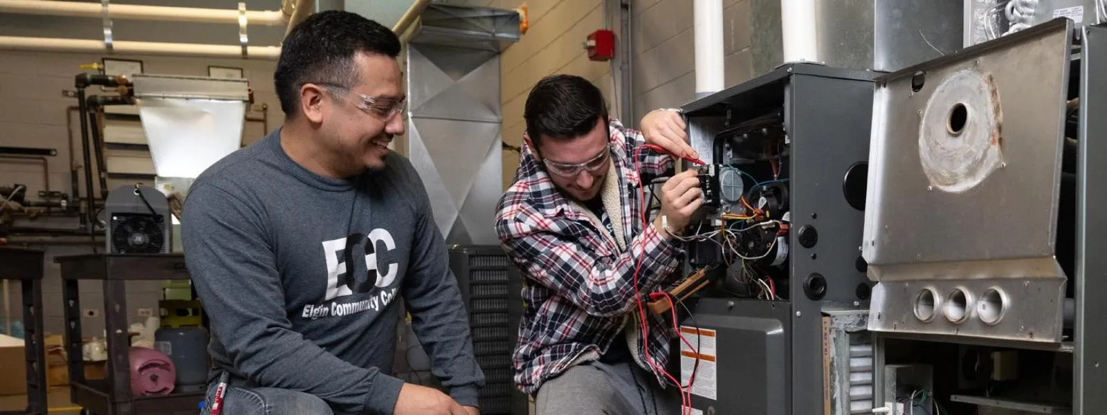 Un estudiante trabaja en una máquina junto a su instructor.