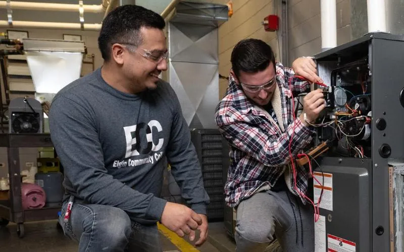 Student working on a machine beside his instructor.