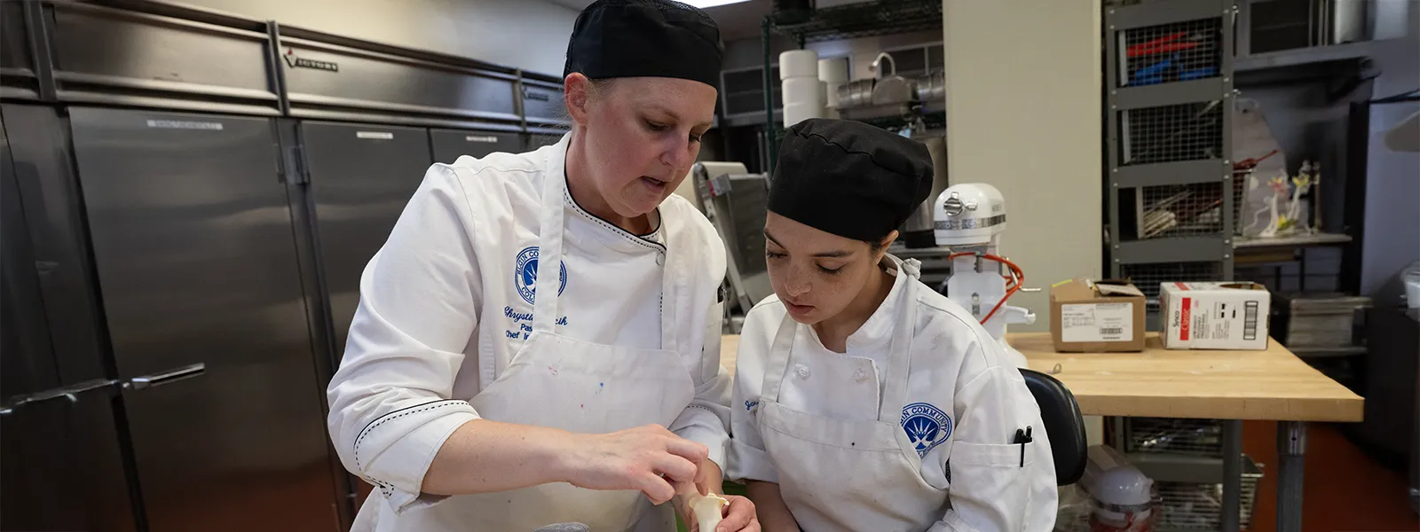 Culinary instructor teaching a student a pastry molding technique