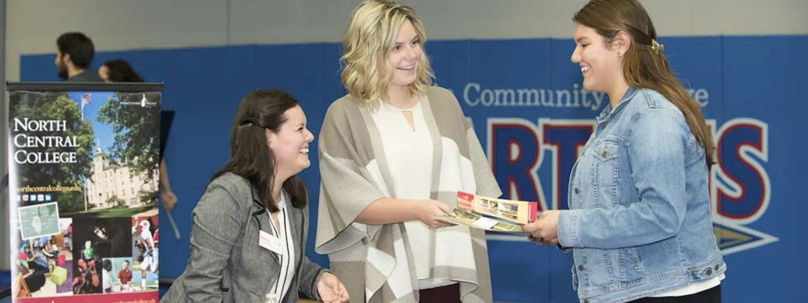 Representatives from North Central College handing materials to student