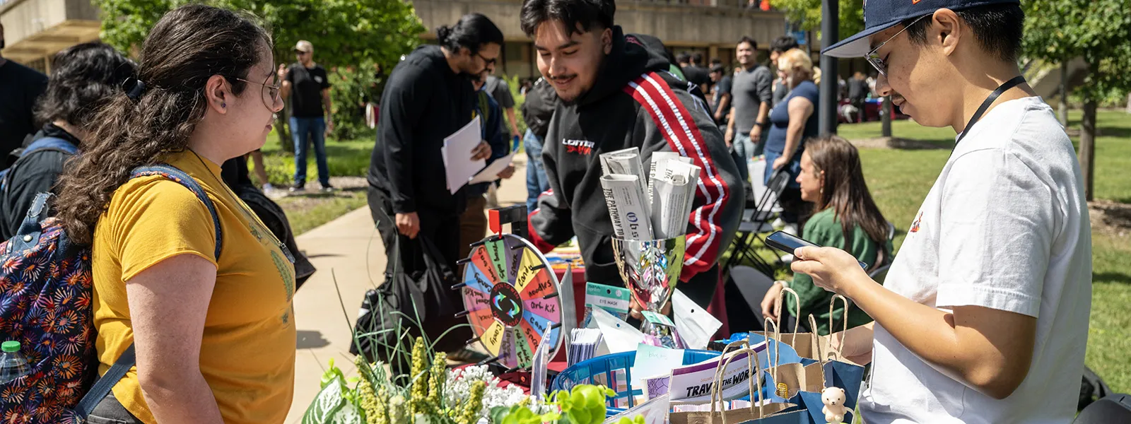 Students work at a table to promote their newspaper with flowers on the table
