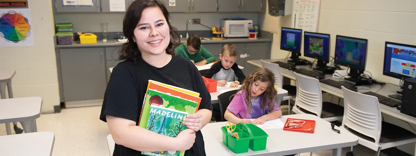 Student holding books in childcare lab
