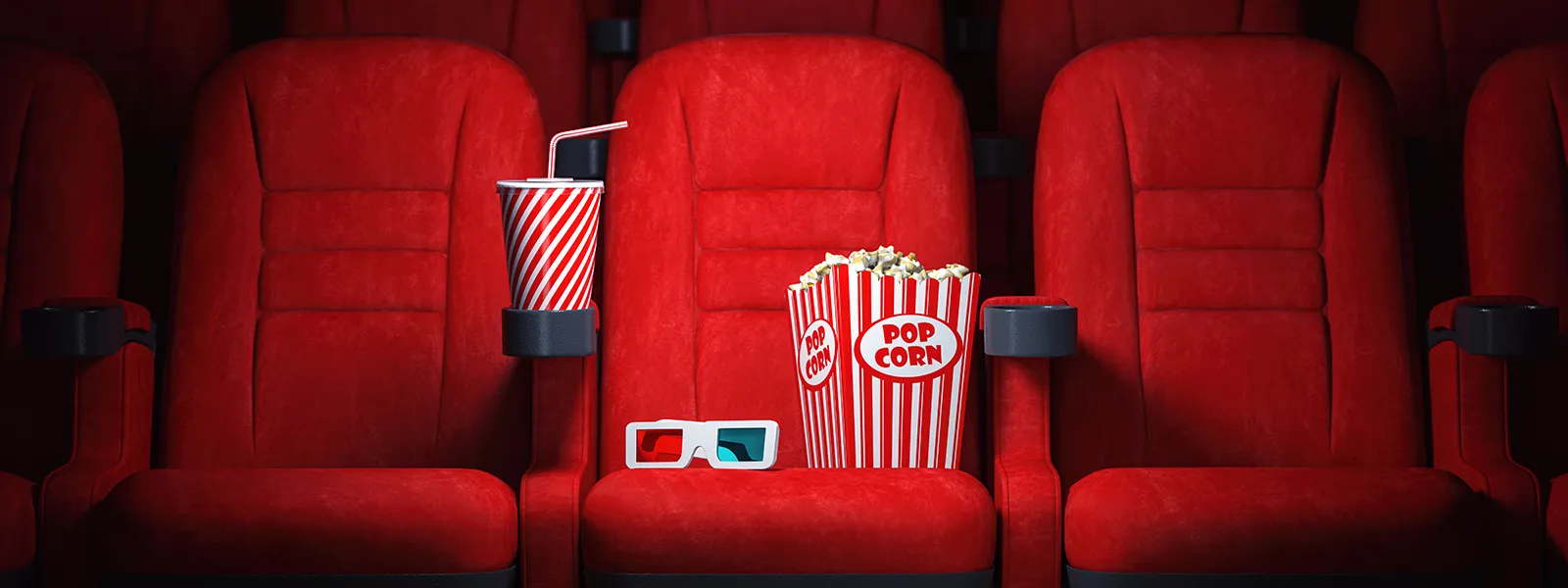 Row of theater seats with one seat containing a box of popcorn, 3D glasses, and a drink.